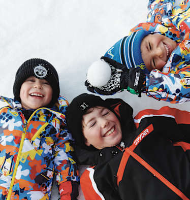 Drei Kinder liegen im Schnee in See.