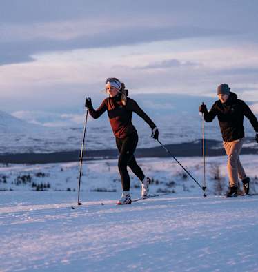 Drei Personen üben die nordische Disziplin Langlaufen aus