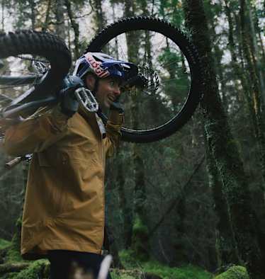 mann hat sein mountainbike auf den schultern, im wald