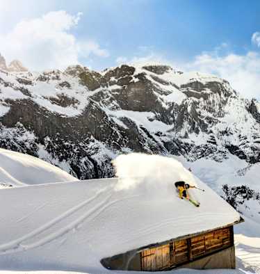 Ein Freerider fährt über das Dach einer Hütte.