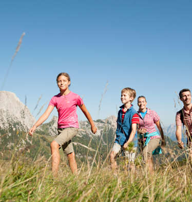 Eine Familie wandert auf einer Alm.