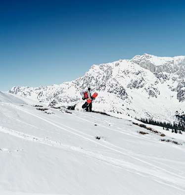 Ein Snowboarder steht in der Winterlandschaft mit Blick auf den Hochkönig.