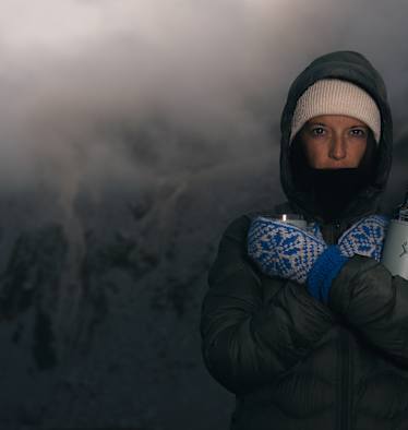 Person in Winterkleidung mit Thermosflasche Hydro Flask Hot Flask & Cup in verschneiter Berglandschaft bei Nebel und eisigen Temperaturen.