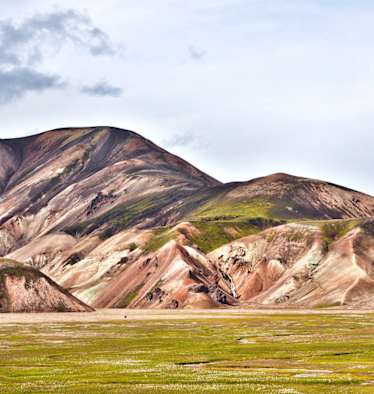 Landmannalaugar: Einsamer Wanderer in der Vulkanlandschaft von Landmannalaugar im Hochland. Buntes Rhyolith-Gestein teils mit Moos überwachsen.