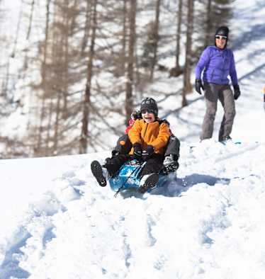 Zwei Kindern beim Bobfahren in der Natur.