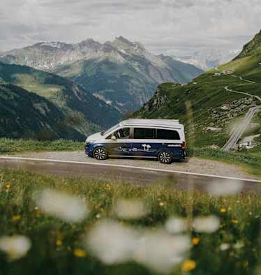 Ein Roadsurfer-Campervan steht am Straßenrand, Blick in die Berge