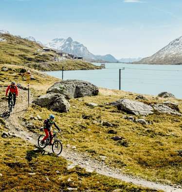 Mountainbiker fahren neben einem See.