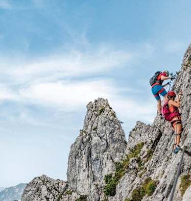 Kletterer am Pidinger Klettersteig und im Hintergrund das Alpenvorland