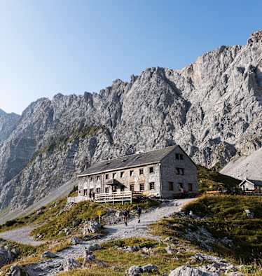 Blick auf die Lamsenjochhütte, die vor gewaltigen Felswänden im Karwendel steht