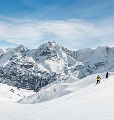 Zwei Schneeschuhwanderer vor atemberaubendem Bergpanorama.