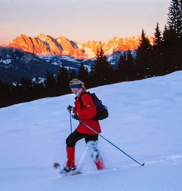 Alpenglühen: Schneeschuhwanderin vor Bergpanorama