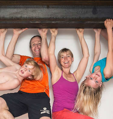 Eine Familie hängt mit den Händen auf einem Eisenträger in der Luft