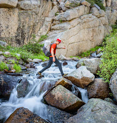Rab Muon 50L Wanderrucksack mann geht über wasserfall