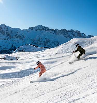 Skifahren in der Schweiz, Berge, zwei Skifahrer, Piste