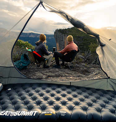 Sea to Summit Isomatte und Kissen im Zelt mit Blick auf zwei Camper, die den Sonnenuntergang in den Bergen genießen