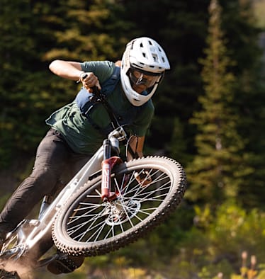 Eine Frau fährt mit dem Mountainbike Waldstrecken ab und trägt dabei einen Helm von ABUS.