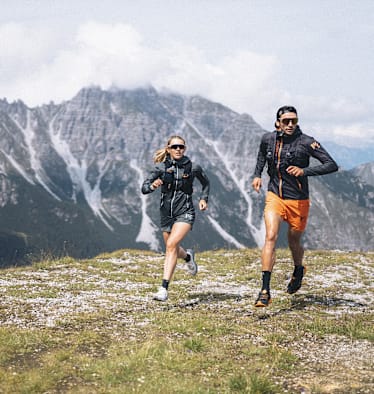 Eine Dame und ein Mann laufen zusammen auf dem Berg.