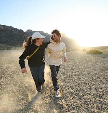 Zwei Personen lachend in der freien Natur mit Kleidung von Maier Sports.