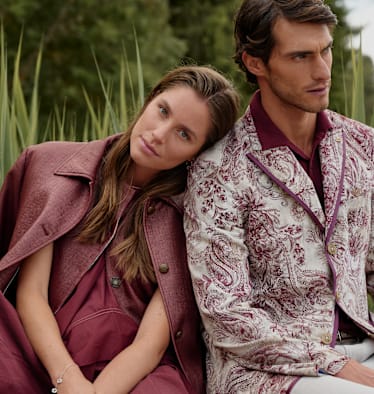 Ein Mann und eine Frau im Freien bei einem See in modischer Kleidung in Rottönen.