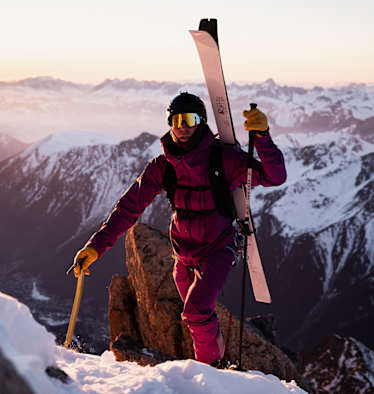 Eine Person steigt mit Tourenski am Rücken auf einen Berg