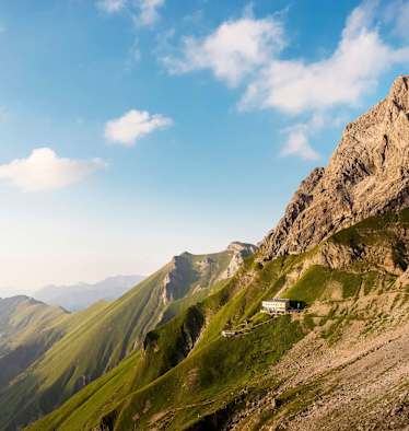 Das Waltenbergerhaus ist eingebettet in eine alpine Graslandschaft