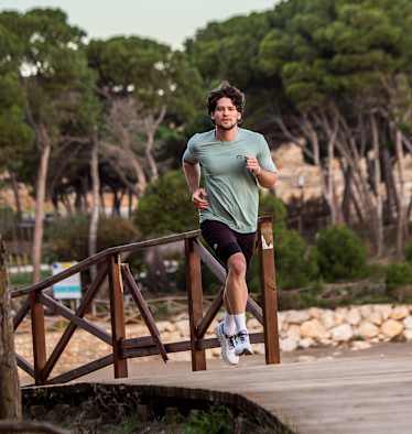 Ein Mann läuft im neuen Trailrunning-Outfit von skinfit über eine Brücke aus Holz.