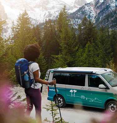 Frau wandert durch die Alpen, unterwegs mit den roadsurfer Camper