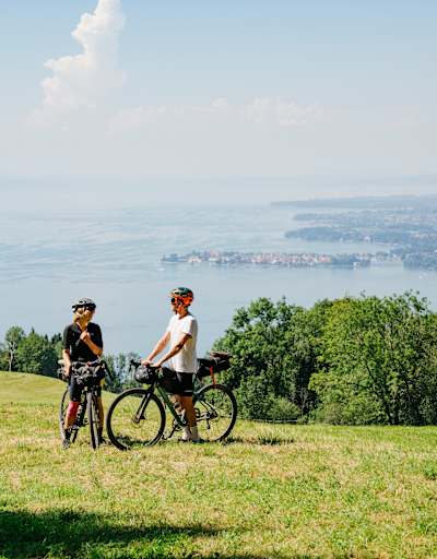 zwei Gravelbiker stehen auf Wiese, im Hintergrund der Bodensee