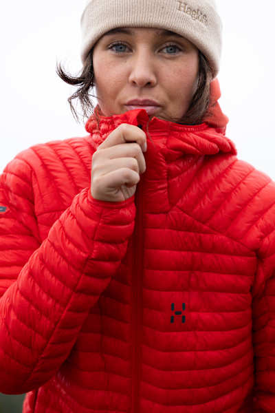 Nahaufnahme einer roten Isolationsjacke mit leichtem Steppmuster, perfekt für Outdoor-Aktivitäten bei kaltem Wetter.