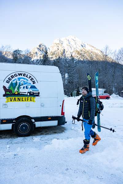 Skitourengeher mit Van im Hintergrund