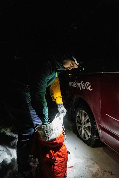 Bergsteiger in der Nacht beim Packen seines Rucksacks
