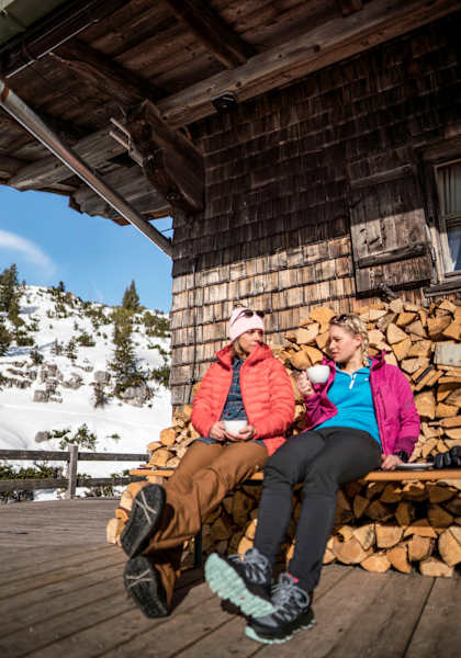 Zwei Frauen trinken Cappuccino vor einer Hütte