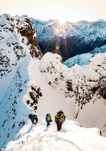 Eine Seilschaft bei Sonnenaufgang am Weg auf den Gipfel