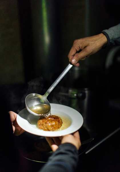 Die Kaspressknödelsuppe wird auf die Teller verteilt