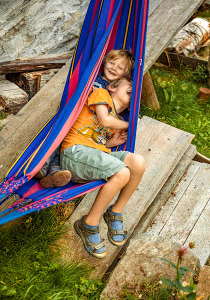 Zwei Kinder liegen in einer Hängematte und freuen sich.