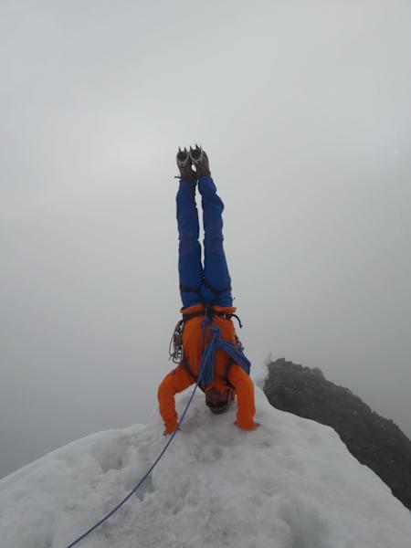 Bergführer Patrick lässt sich trotz Schlechtwetter den Gipfelkopfstand nicht nehmen