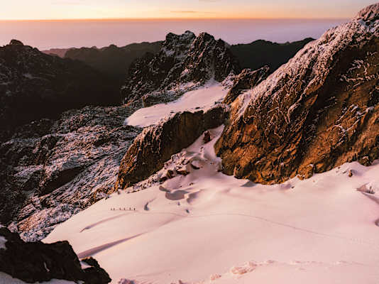 Das Expeditionsteam im sanften Morgenrot auf seinem Weg über den Gletscher. Seit der Erstbesteigung im Jahr 1906 schmilzt das Eis dahin.