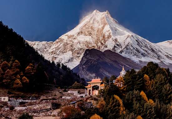 Ein Kloster und dahinter der mächtige Manaslu im Licht des Morgens