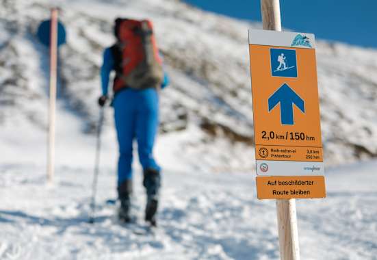 Das Pistentourenleitsystem des Landes Tirol mit orangen Hinweisschildern zeigt den sicheren Weg nach oben.