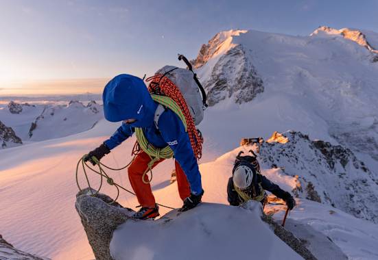Ein Bergsteiger mit der neuen Mammut Eiger Extreme Kollektion klettert über einen verschneiten Felsgrat. Am kurzen Seil sichert er einen Nachsteiger, der mit einem Eispickel unterwegs ist.