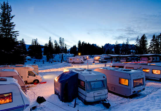 Der Wintercampingplatz Jaunpass bei Nacht. Es liegt Schnee und die Wohnwagen sind hell erleuchtet.