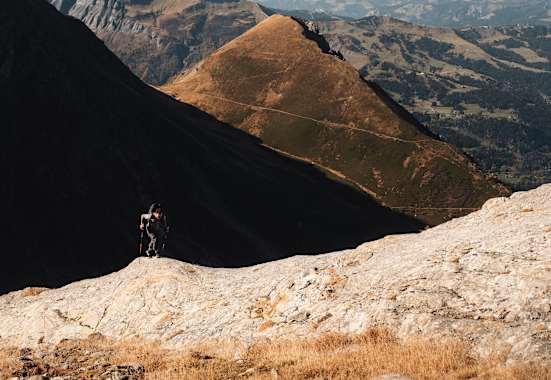 Ein Alpinist steigt einen Berg mit zwei Stöcken und der Haglöfs L.I.M ZT 2.0-Serie hinauf.
