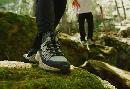 Der Wild Hike Wanderschuh von Jack Wolfskin auf bemoostem Stein in Wald.