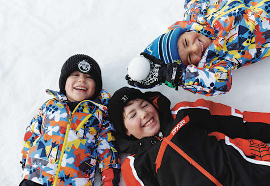 Drei Kinder liegen im Schnee in See.