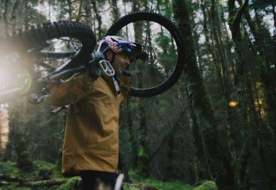 mann hat sein mountainbike auf den schultern, im wald
