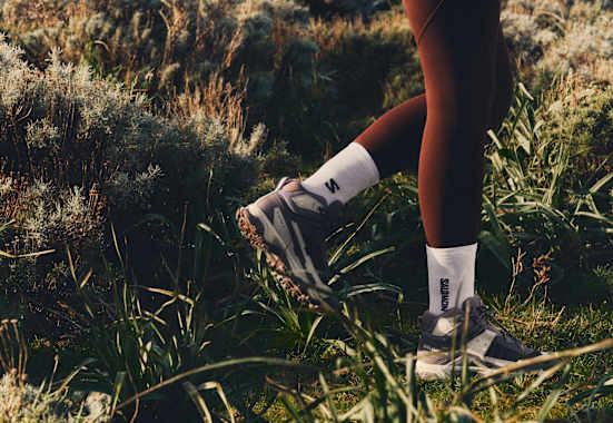 füße in salomon ausrüstung im gras beim wandern