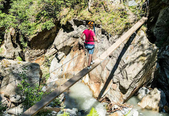 Mädchen im Klettersteigset beim Balancieren auf einem Baumstamm in der Feeschlucht
