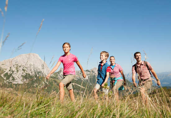 Eine Familie wandert auf einer Alm.