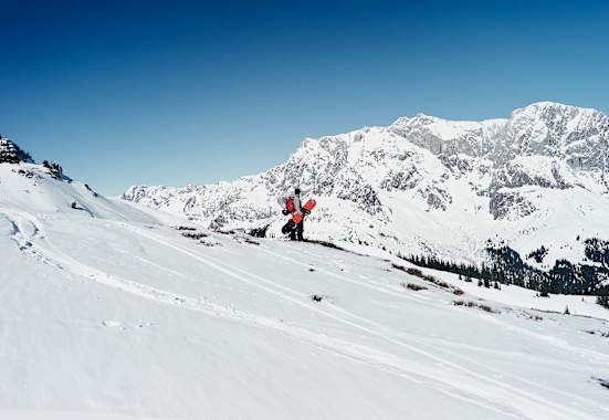 Ein Snowboarder steht in der Winterlandschaft mit Blick auf den Hochkönig.