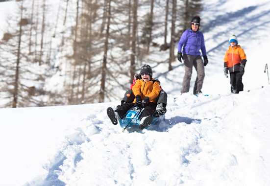 Zwei Kindern beim Bobfahren in der Natur.